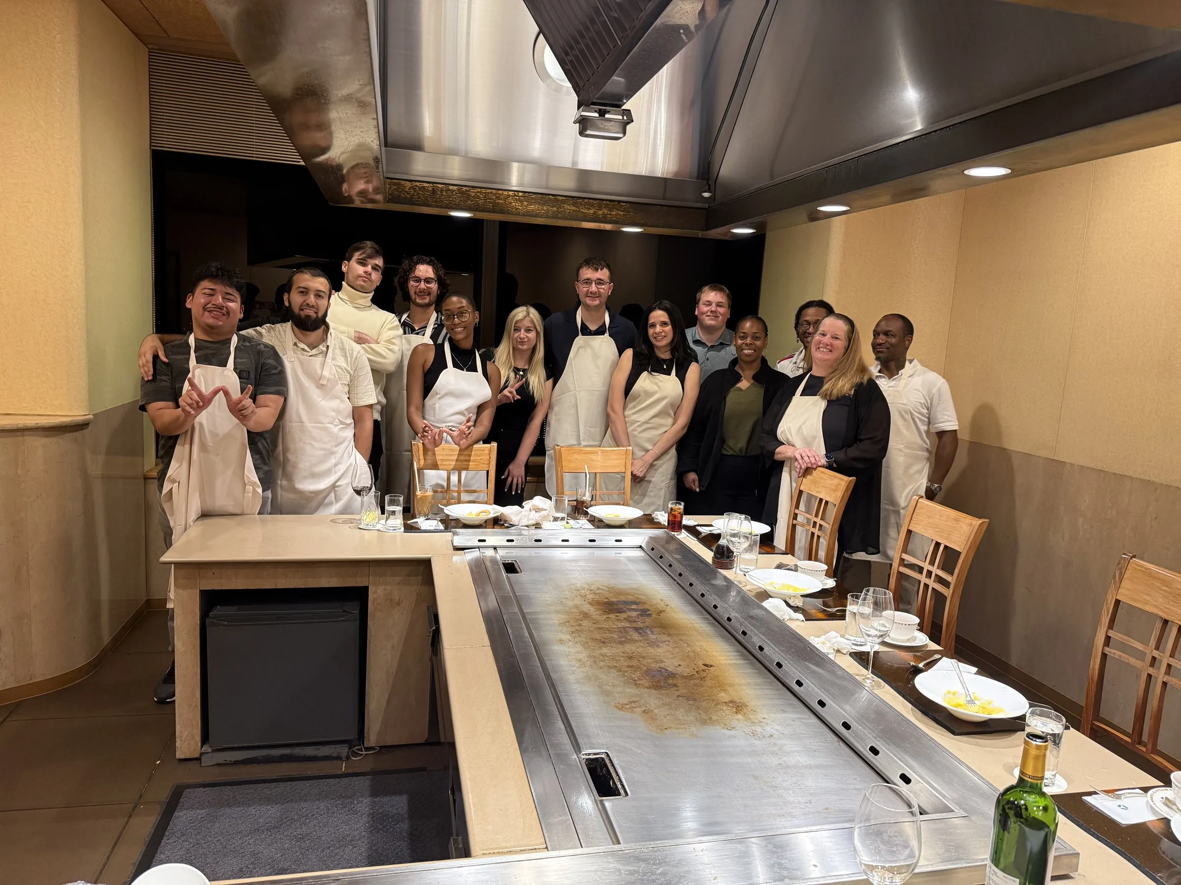 The group standing together in aprons behind the teppanyaki griddle at the end of the meal.