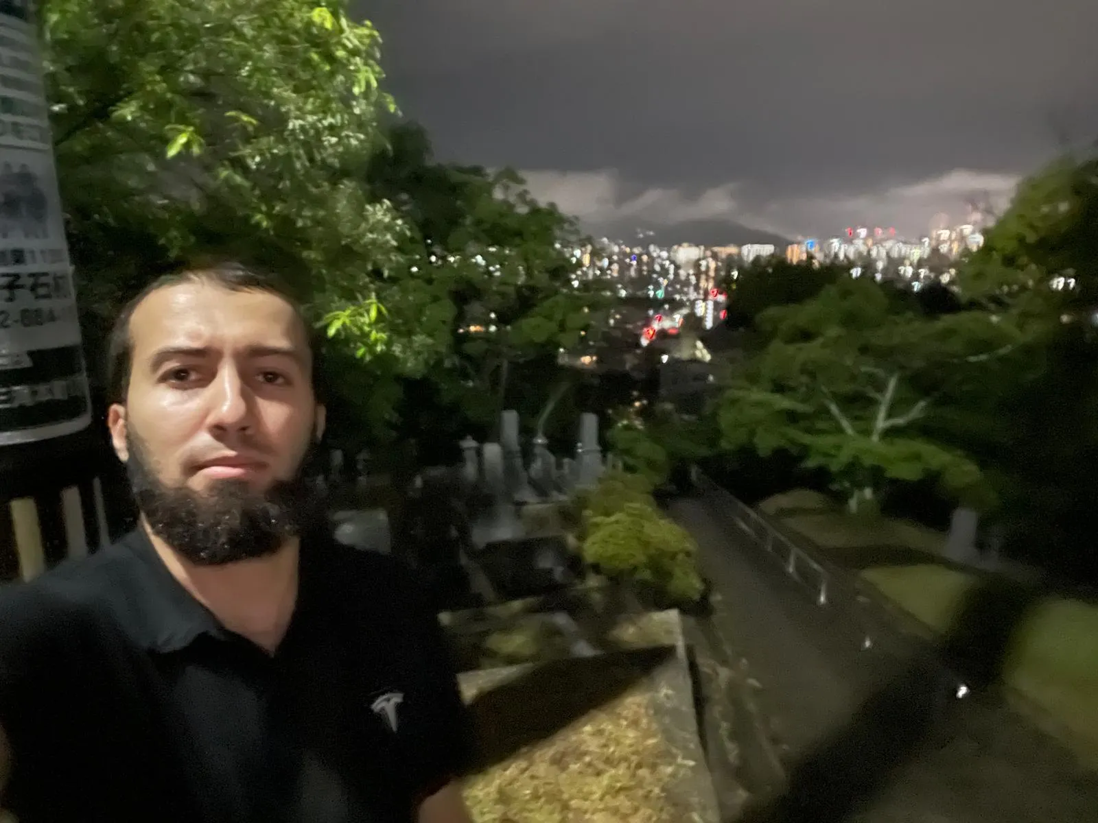 Gotibeh at night on a dark hillside above Hiroshima with the city lights below.