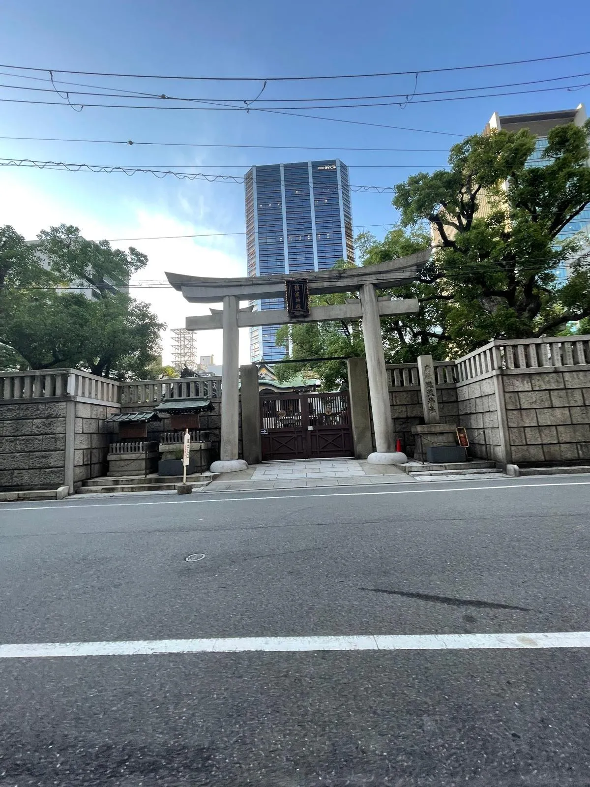 A weathered stone torii gate framed by trees on a path in Hiroshima.